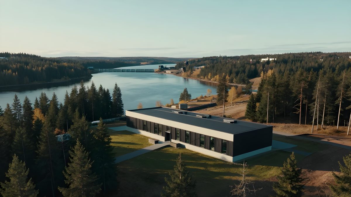 Modern datacenterbyggnad vid en svensk älv med vattenkraftsdamm och granskog, nordiskt landskap i höstljus