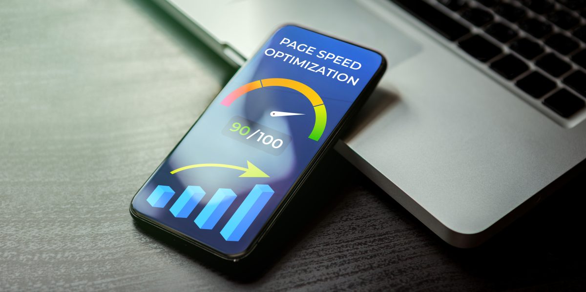 En smartphone visar en sidhastighetsmätare på 90 av 100 och ett stigande stapeldiagram, lutad mot en bärbar dator