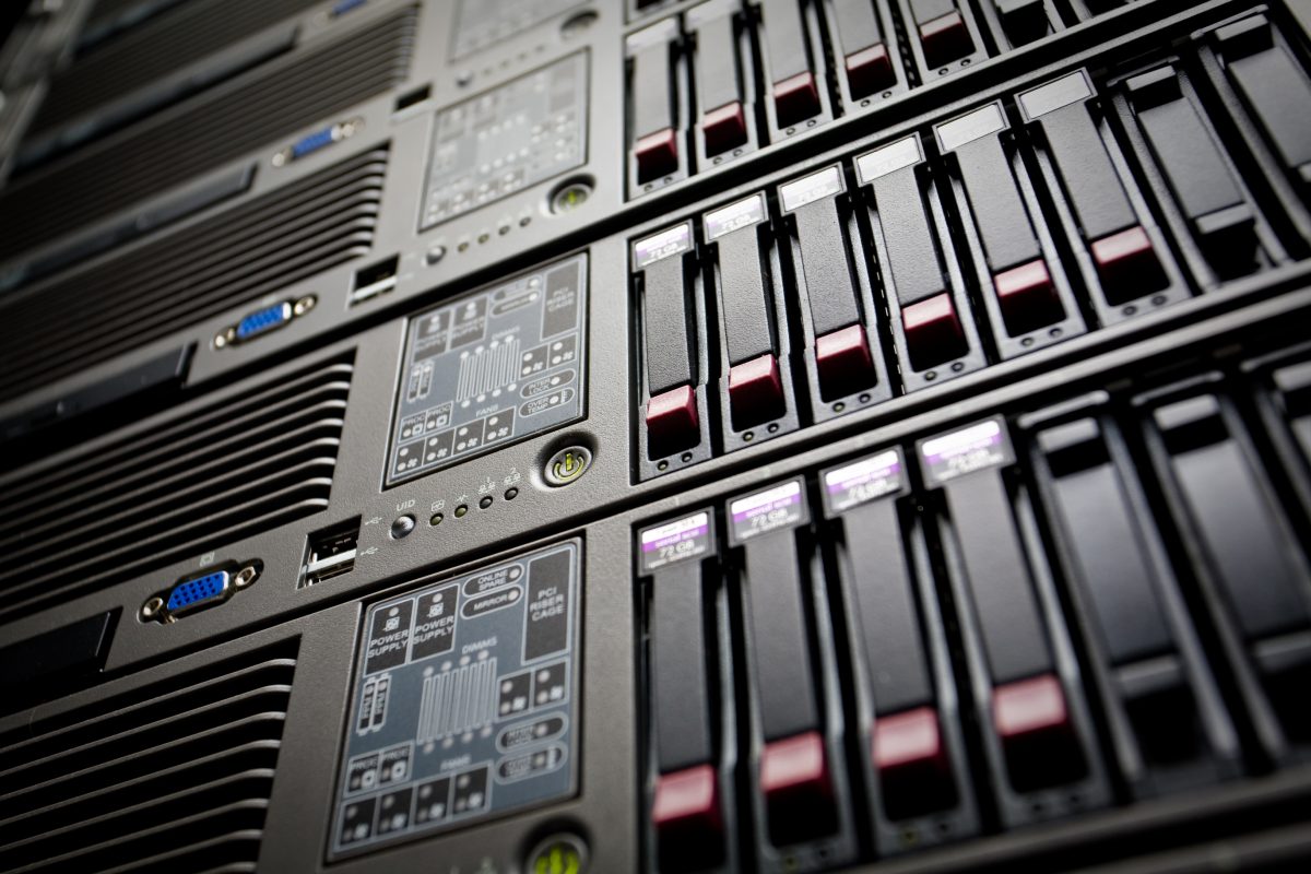 Närbild snett underifrån på ett serverrack i ett datacenter med rader av utbytbara hårddiskar i fronten och tänd statusindikator på varje enhet. Bilden illustrerar var webbhotellets dagliga backup fysiskt lagras.