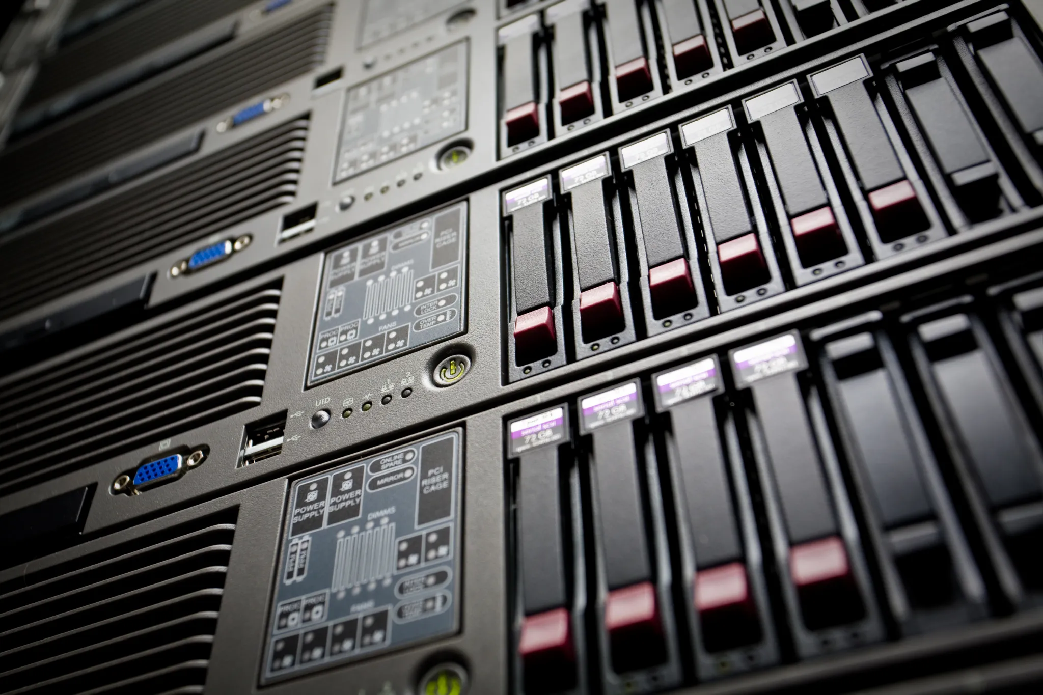 Närbild snett underifrån på ett serverrack i ett datacenter med rader av utbytbara hårddiskar i fronten och tänd statusindikator på varje enhet. Bilden illustrerar var webbhotellets dagliga backup fysiskt lagras.